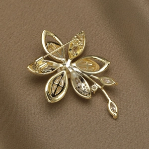 Broche camélia dorée élégante avec incrustations de nacre et zircons sur satin brun