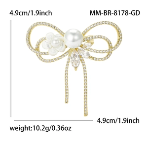 Broche nœud dorée élégante avec cristaux de zircon, perle et accents de fleurs blanches