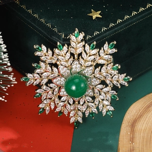 Detailed close-up of a luxury snowflake brooch with green zircon on a velvet box