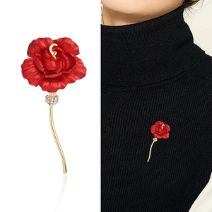 Elegant red rose brooch with crystals and gold curved stem shown on a black sweater
