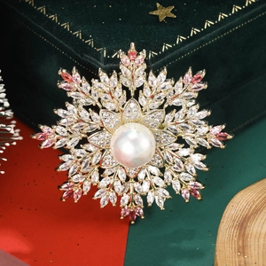 Macro detail of snowflake brooch with pink cubic zirconia and a white pearl center