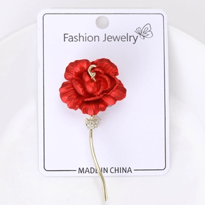 Detail view of a vintage red rose brooch with gold stem and sparkling rhinestones