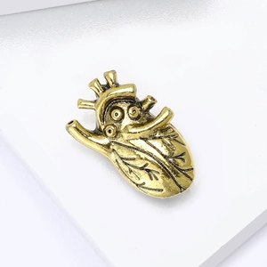 Vintage gold anatomical heart brooch with detailed vascular structure on white background