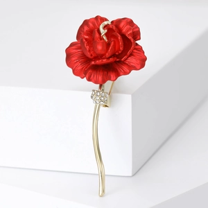 Elegant red rose brooch with gold stem and sparkling zircons on a white platform