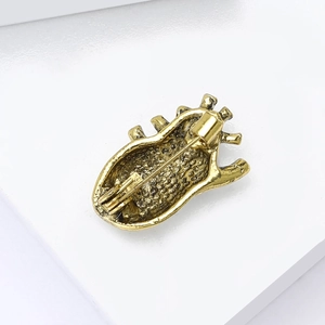 Macro view of anatomical heart brooch showing vintage gold finish and pin mechanism