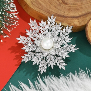 Close-up of snowflake brooch with white pearl and sparkling zircons on festive background