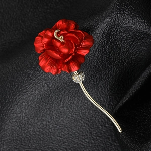 Detailed macro view of a red metal rose brooch with gold accents and diamond inlay