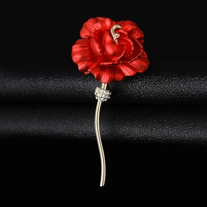 Detail of red rose brooch with enamel petals and sparkling rhinestones on black leather