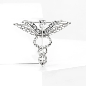 Detailed view of a silver caduceus brooch with sparkling rhinestones on a white pedestal