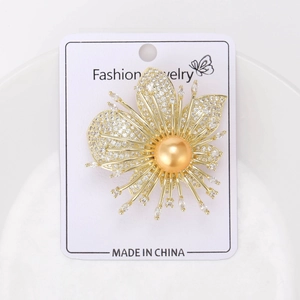 Détail d'une broche orchidée avec zircons sertis et une grande perle dorée