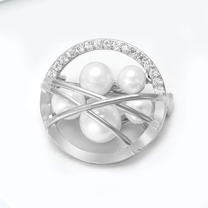 Macro shot of silver circular brooch with tiny zircons and five white pearls