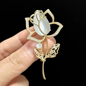 Détail d'une broche rose avec pierre oeil de chat et cristaux sertis sur métal doré