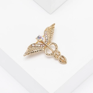 Close-up of golden Caduceus brooch with colorful rhinestones and wings detail
