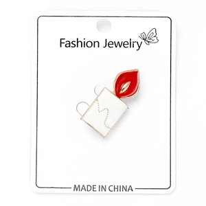 Detail of creative enamel candle brooch with red flame on fashion jewelry card