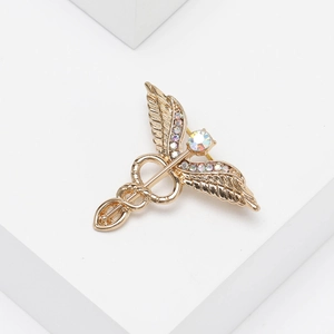 Macro view of golden caduceus brooch with colorful rhinestones on a white background
