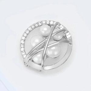 Detail of a round brooch featuring four white pearls and micro-set zircon stones