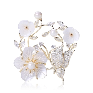 Détails de la broche fleur en nacre naturelle avec papillon en zircon et perles blanches