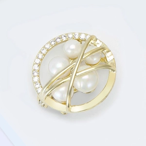 Macro detail of round gold brooch featuring white pearls and micro-pave cubic zirconia