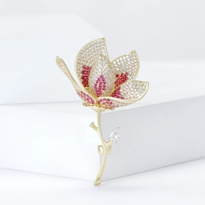 Elegant gold tulip brooch with pink and white cubic zirconia on a minimalist podium