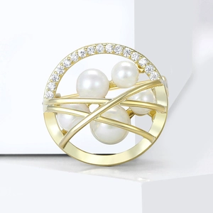 Elegant gold round brooch with white pearls and micro-set cubic zirconia on white steps