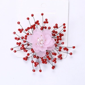 Detail of handmade pink fabric flower brooch with red faceted beads and crystal center