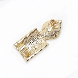 Detail showing the safety pin clasp and textured alloy back of the candle brooch