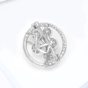 Close-up of circular silver brooch back with safety pin clasp and pearl setting detail