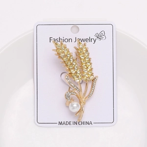 Close-up of golden wheat stalk brooch with yellow crystals and elegant white pearl detail