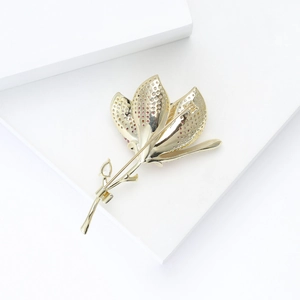 Close-up of golden tulip brooch with pink micro-set cubic zirconia and polished details