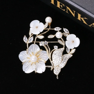 Macro de broche fleur en nacre avec perles et papillon en zircon sur velours