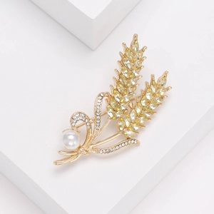 Elegant gold wheat brooch with yellow crystals and pearl on a white pedestal