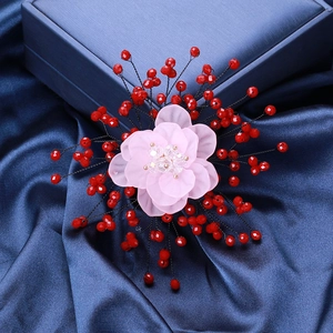Detail of handmade flower brooch with pink resin petals and red beads on blue satin