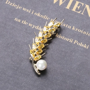 Detail der Weizenähren-Brosche mit gelbem Zirkon und Perle auf antikem Buchhintergrund