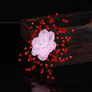 Macro detail of handmade resin flower brooch with red crystal beads on wood tray