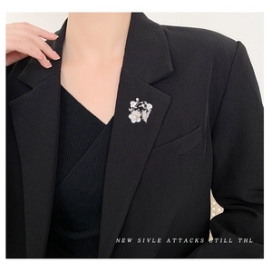 Broche fleur en nacre et papillon doré avec zircons sur un blazer noir style chic français