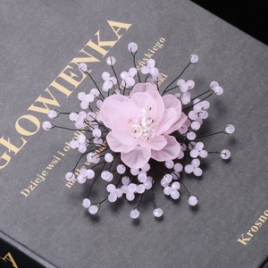 Close-up of handmade pink crystal flower brooch with pearls on a vintage book