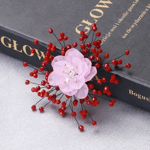 Macro view of handmade pink chiffon flower brooch with crystals and red beads