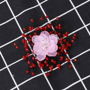 Detail of pink crystal flower brooch with pearl accents on a black and white checkered fabric