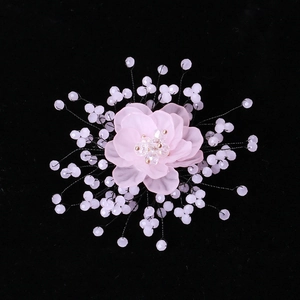 Macro detail of floral brooch with pink translucent petals and crystal bead stamens