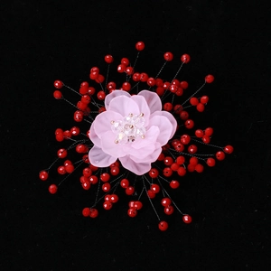 Macro shot of handmade floral brooch with pink resin petals and red beaded detail