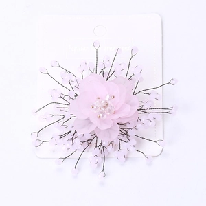 Close-up of pink chiffon flower brooch with pearls and teardrop beads on a display card