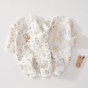 Flat lay of quilted baby rompers featuring forest animals and tropical prints on white and blue
