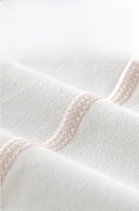 Gros plan sur les coutures plates à quatre aiguilles et six fils d'un body bébé en coton