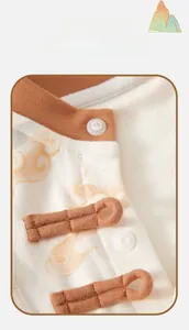 Detail of vintage frog button closure and traditional cloud patterns on baby romper