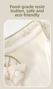 Detail of baby romper with resin snap buttons and soft sage green trim on cotton fabric