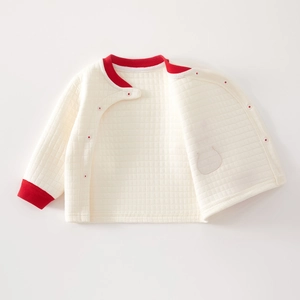 Detail of baby quilted jacket with red trim and cute rabbit embroidery on cream fabric