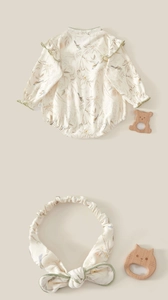Flat lay of cream cotton baby bodysuit with floral patterns and matching bow headband