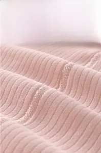 Detailed macro view of pink ribbed fabric showing seamless stitching and soft texture
