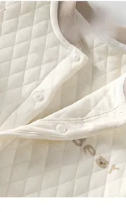 Detail view of baby romper featuring snap buttons and quilted diamond fabric texture