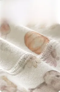 Detailansicht der nahtlosen Flachnaht an weichem Baby-Einteiler aus Baumwolle mit Blumen